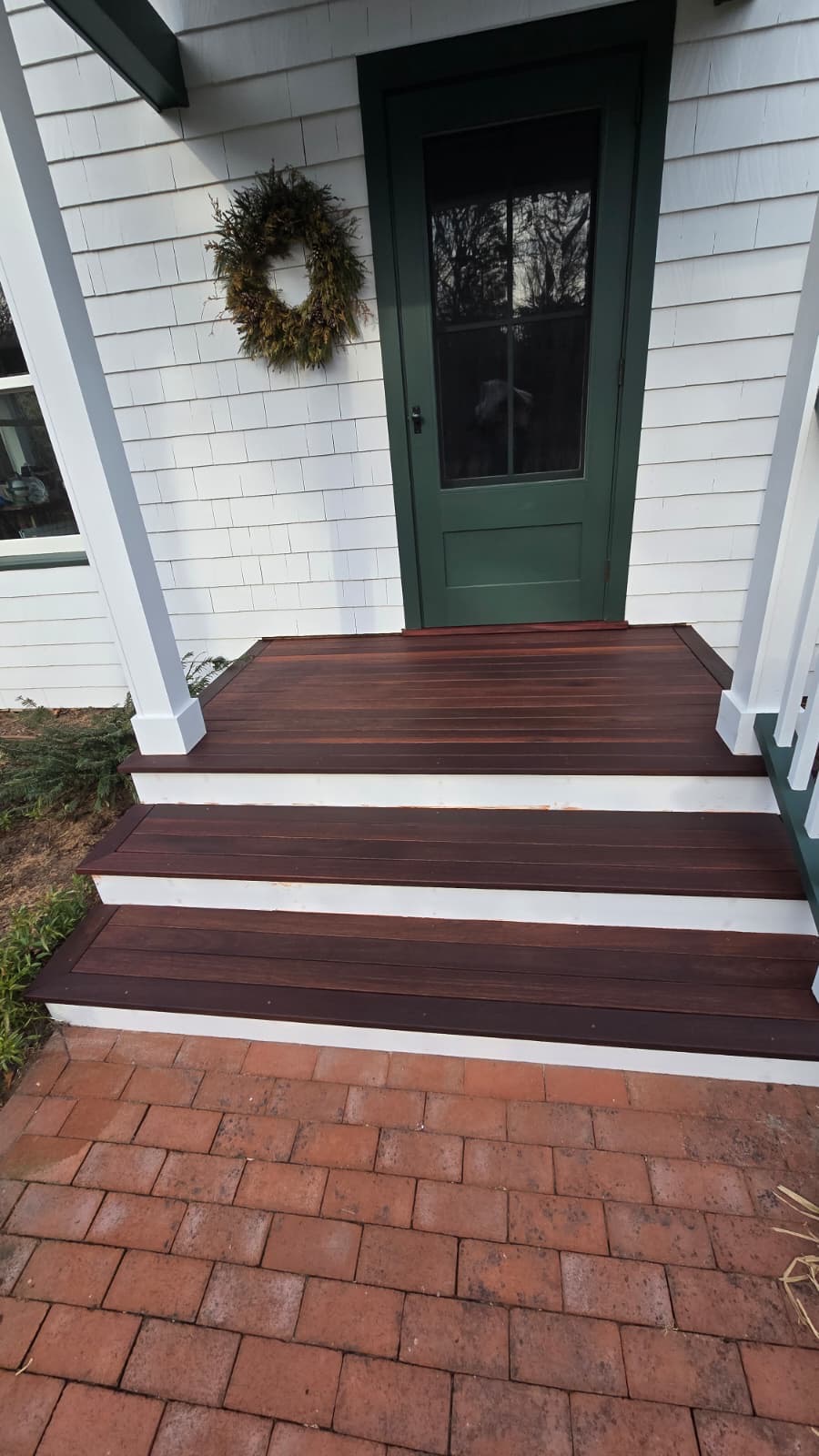 Stained mahogany front porch steps with white trim and green door